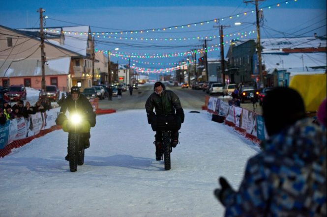 Two cyclists crossing the finish line together and winning The Iditarod Trail Invitational. Photo courtesy Alaska Dispatch News.